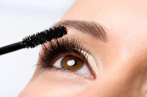 Woman applying mascara on eyelashes